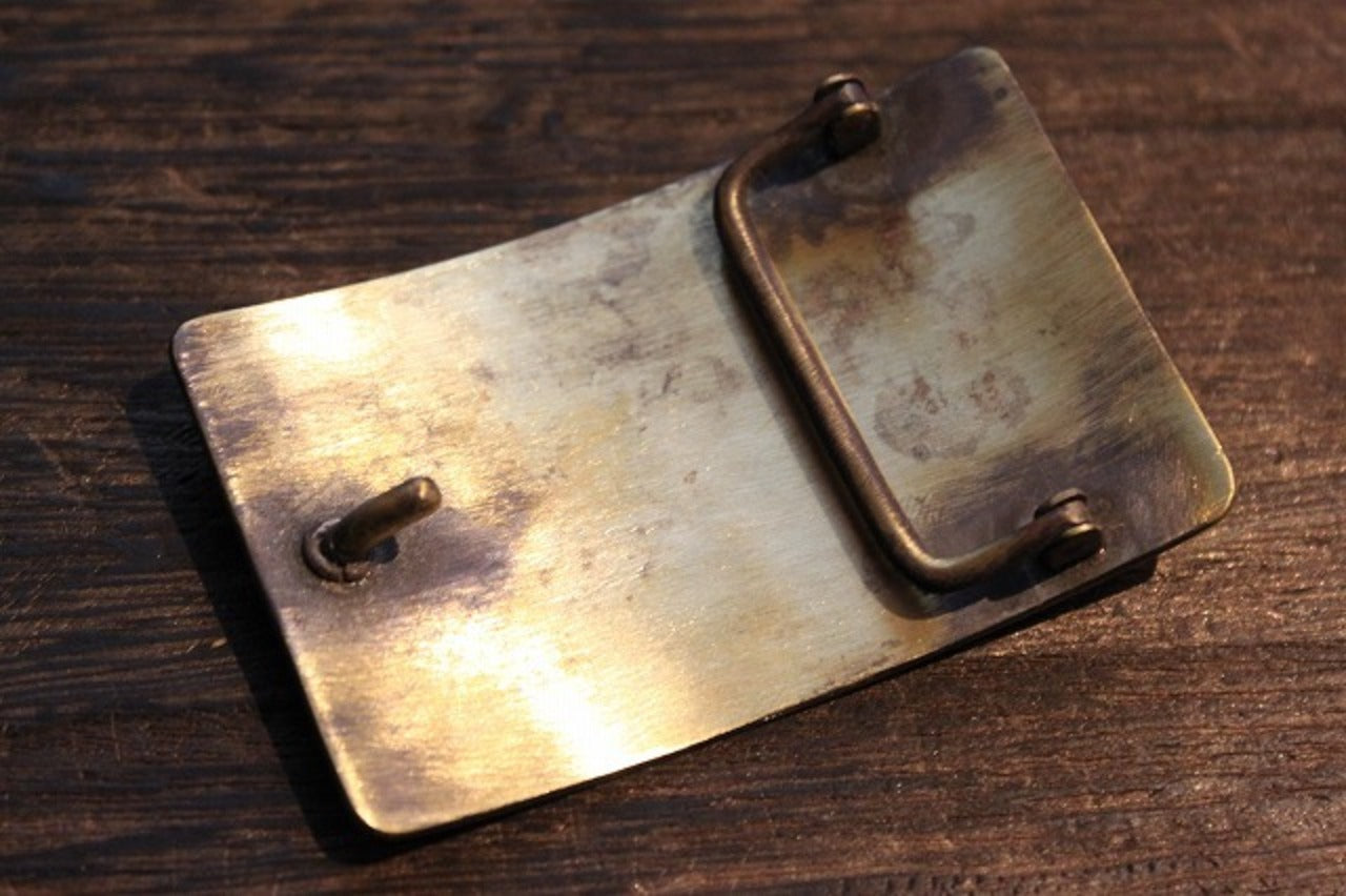 L.O.L.ロゴとクロスボーンモチーフが装飾された、真鍮風のビンテージ調バックル。Laughing Cube Incデザインのファッションアクセサリー画像3