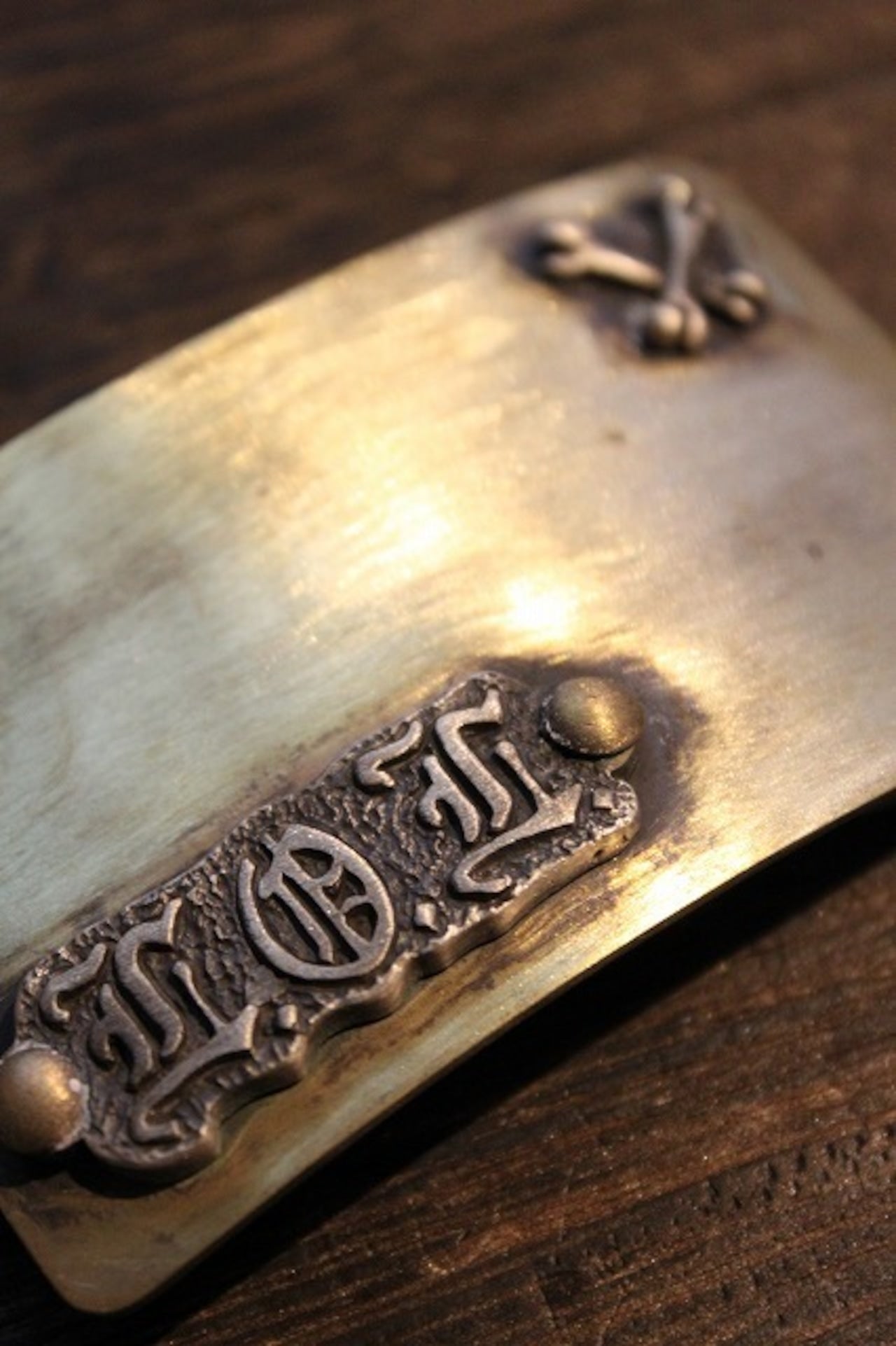 L.O.L.ロゴとクロスボーンモチーフが装飾された、真鍮風のビンテージ調バックル。Laughing Cube Incデザインのファッションアクセサリー画像2