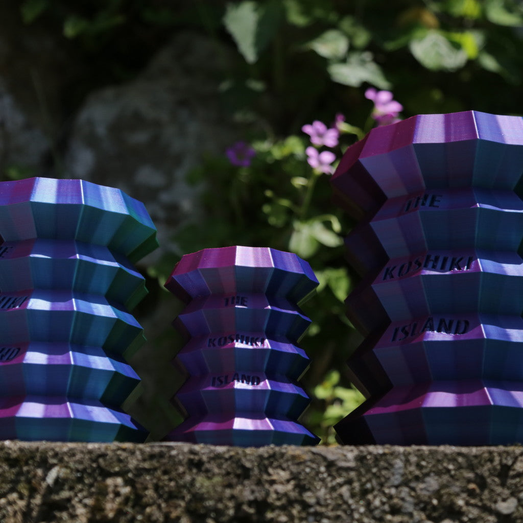 THE KOSHIKI ISLANDの文字が彫られた、光沢のあるグラデーションカラーの多角形カップ。甑島の企業09969.jpが手がけるオリジナルグッズの画像2