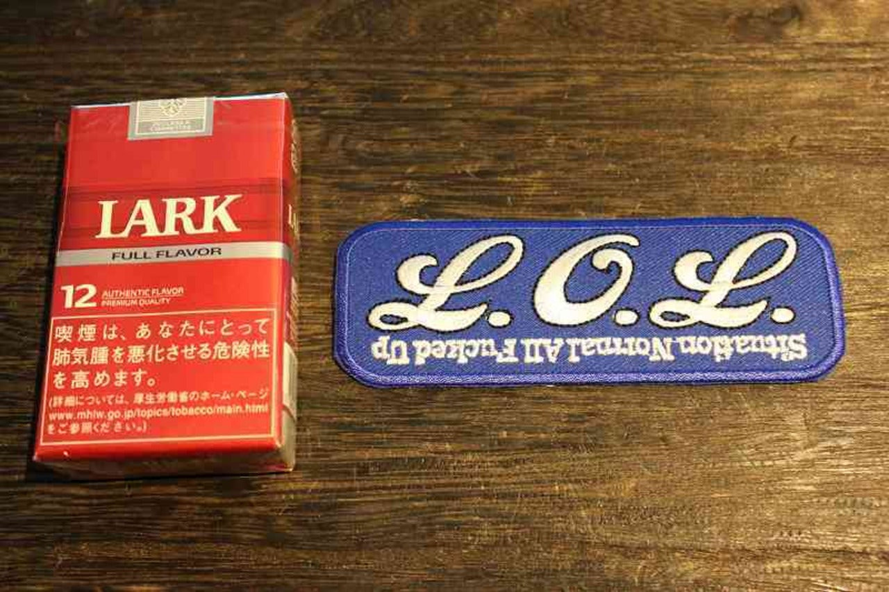 L.O.L. ワッペン・パッチの写真。青地に白い刺繍文字で「L.O.L.」と大きくデザインされ、下部には「Situation Normal All Fucked Up」の文字が逆さに刺繍されたユニークなデザイン。ミリタリーテイストやジョークグッズ、アパレル用のパッチとして人気