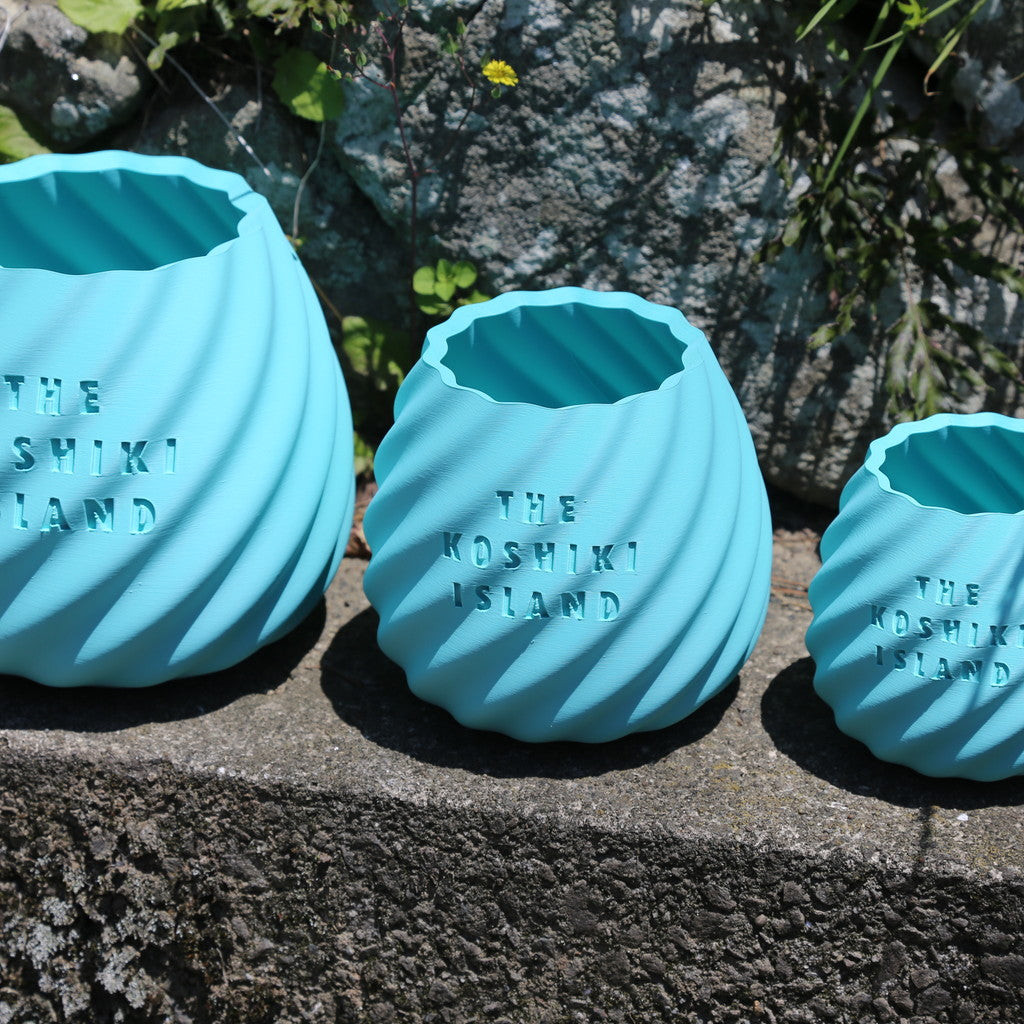 THE KOSHIKI ISLANDの文字が彫られた、水色のマットな質感の多角形カップ。ひねりのある立体形状が特徴で、09969。jpによる甑島オリジナルグッズの画像12