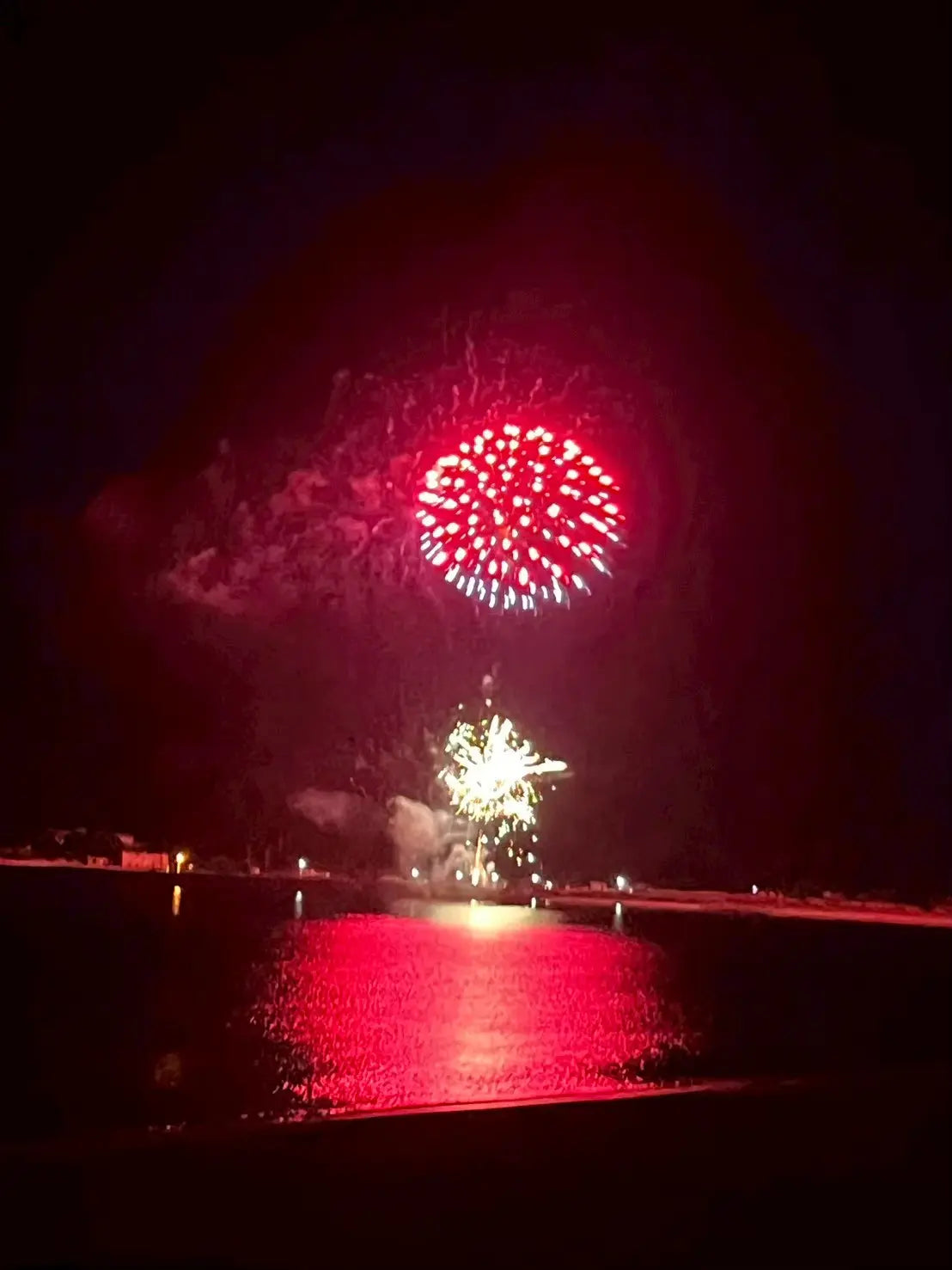 夜空と水面を赤く照らす花火